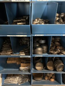 blue metal bins with pipe caps, welding rods, and supplies